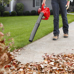 26cc 2-Cycle Handheld Gas Leaf Blower blowing leaves on walkway